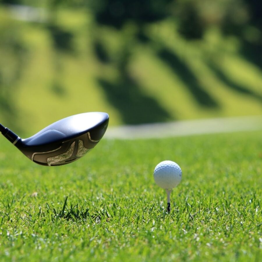 A golf club head close to a golf ball on a tee